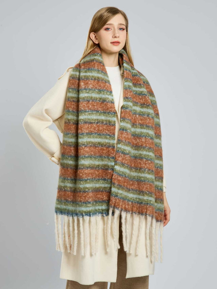 Woman wearing a cream coat and a multi-colored striped scarf with cream fringe