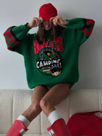 Woman wearing an oversized green knit hoodie with a red beanie and red boots, sitting on a couch