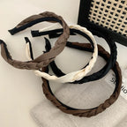 Multiple braided headbands in brown, black, and cream arranged on a surface