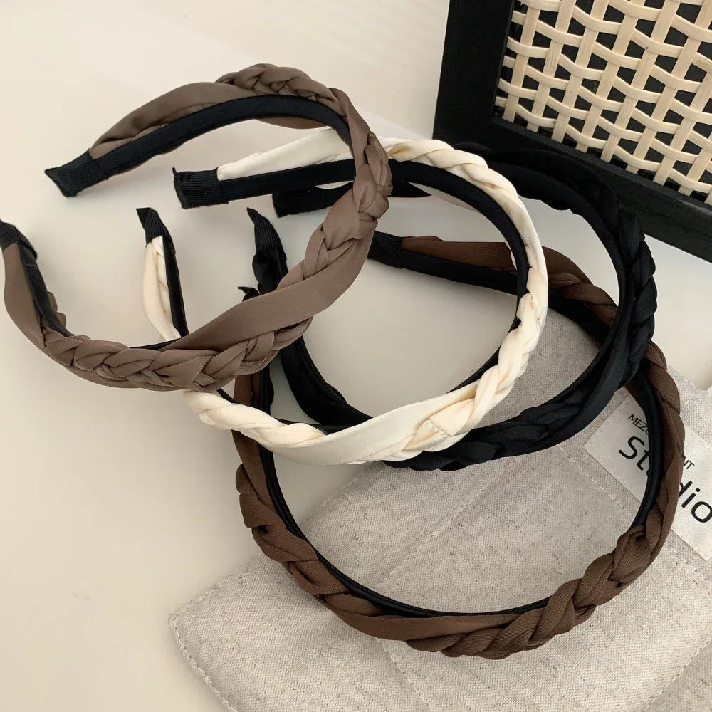 Multiple braided headbands in brown, black, and cream arranged on a surface