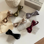 A collection of satin bow hair combs in various colors including champagne, olive green, gray, burgundy, and black, arranged on a white surface.