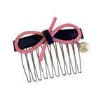A pink and navy hair comb with a bow and pearl.