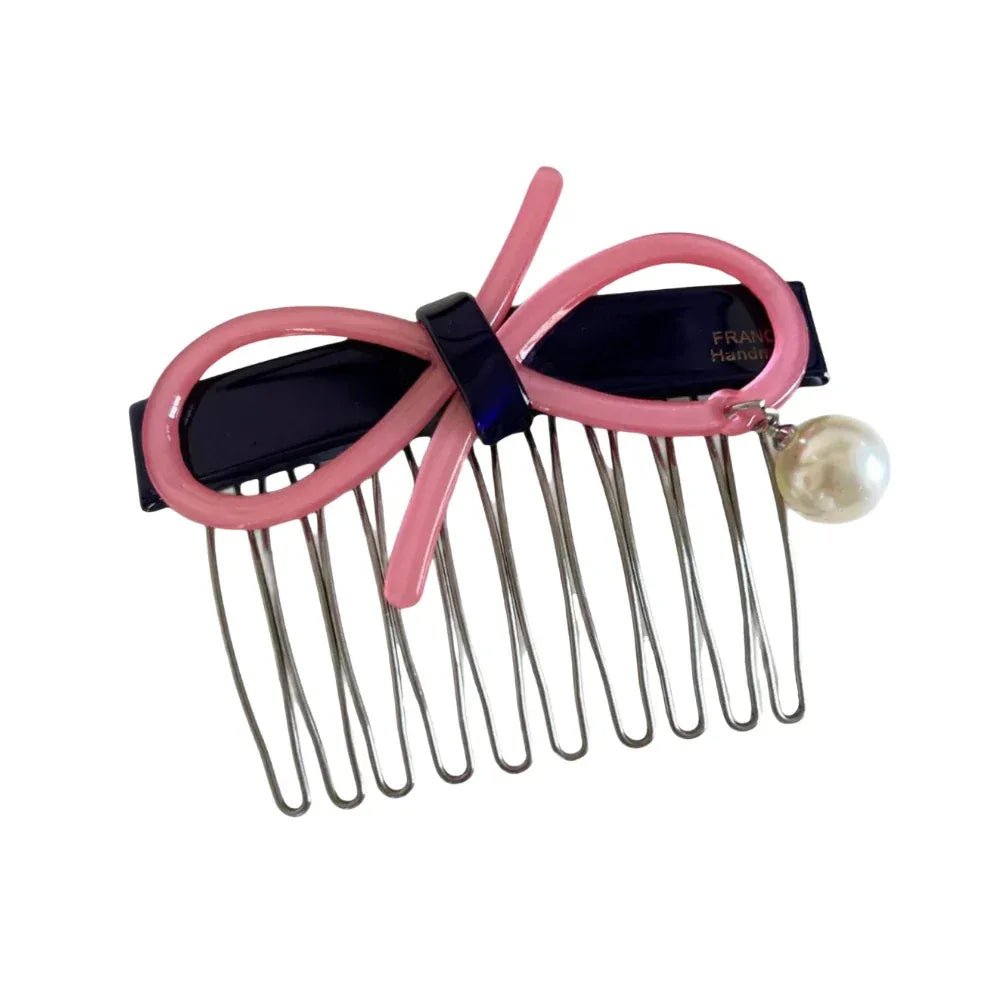 A pink and navy hair comb with a bow and pearl.