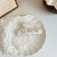 White marble claw clip with three pink heart-shaped embellishments adorned with rhinestones, placed on a white plate with white lace