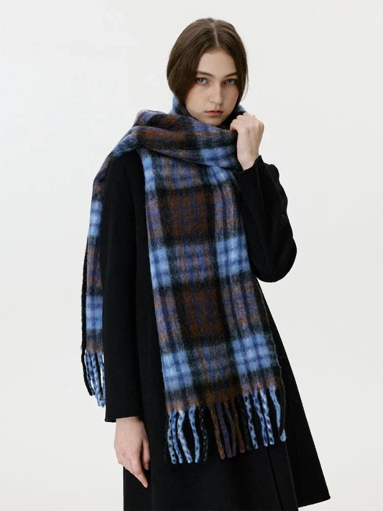 Close-up of a woman adjusting a blue and brown plaid scarf with fringe.