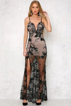 Woman in a long black sequined and appliqued sheer dress with a high slit and deep V-neck