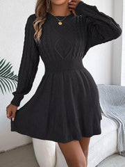 Woman wearing a black long-sleeved knit dress with cable knit detailing on the bodice, adjusting the skirt.