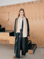 Full body shot of a woman in a leather coat and plaid scarf.