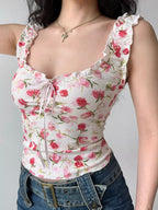 Front view of a woman wearing a white floral print top with short ruffle sleeves and a tie front.