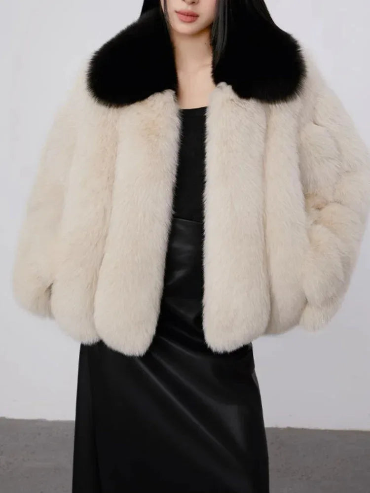 Front view of a cream faux fur cropped jacket with a black collar.