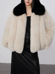 Front view of a cream faux fur cropped jacket with a black collar.