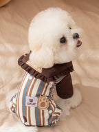 Side view of a white dog in a brown and tan striped jumpsuit with a paw print appliqué.