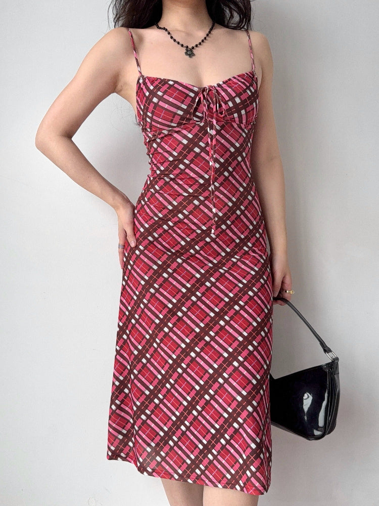 Front view of a woman in a red plaid midi dress, showcasing the fitted silhouette and spaghetti straps.
