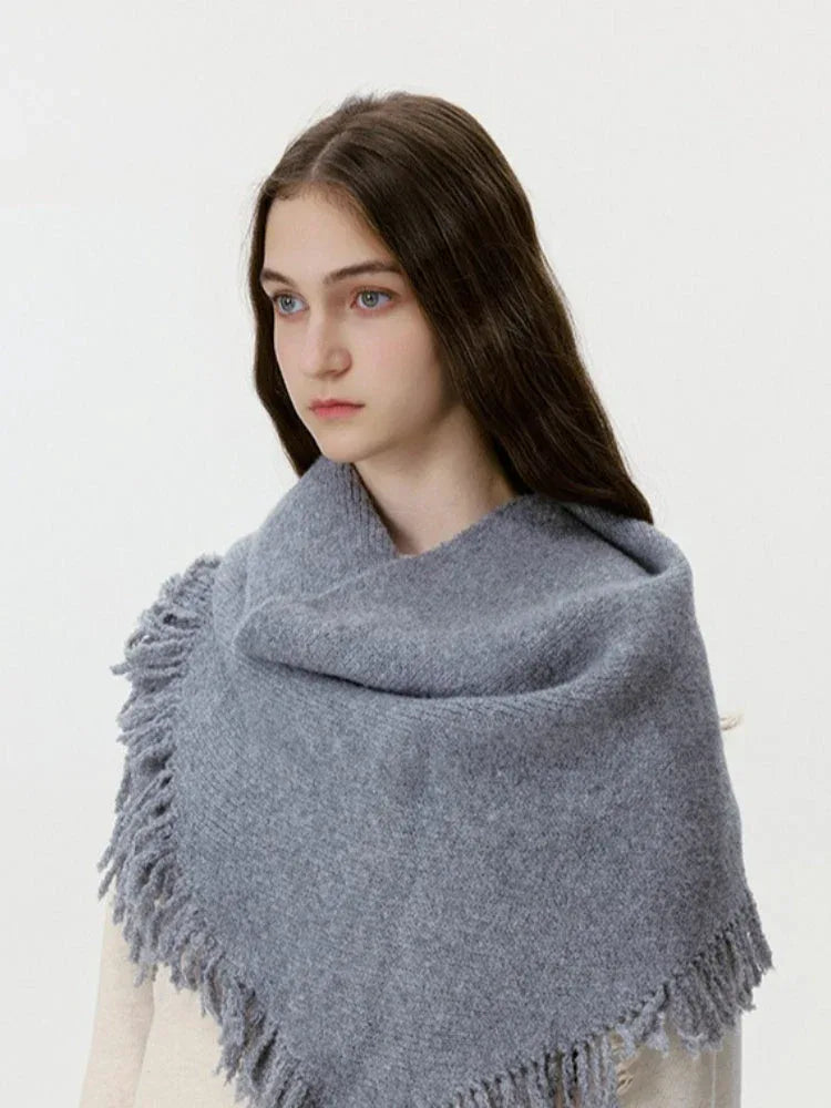 Close-up of a grey fringed scarf draped around a model's neck