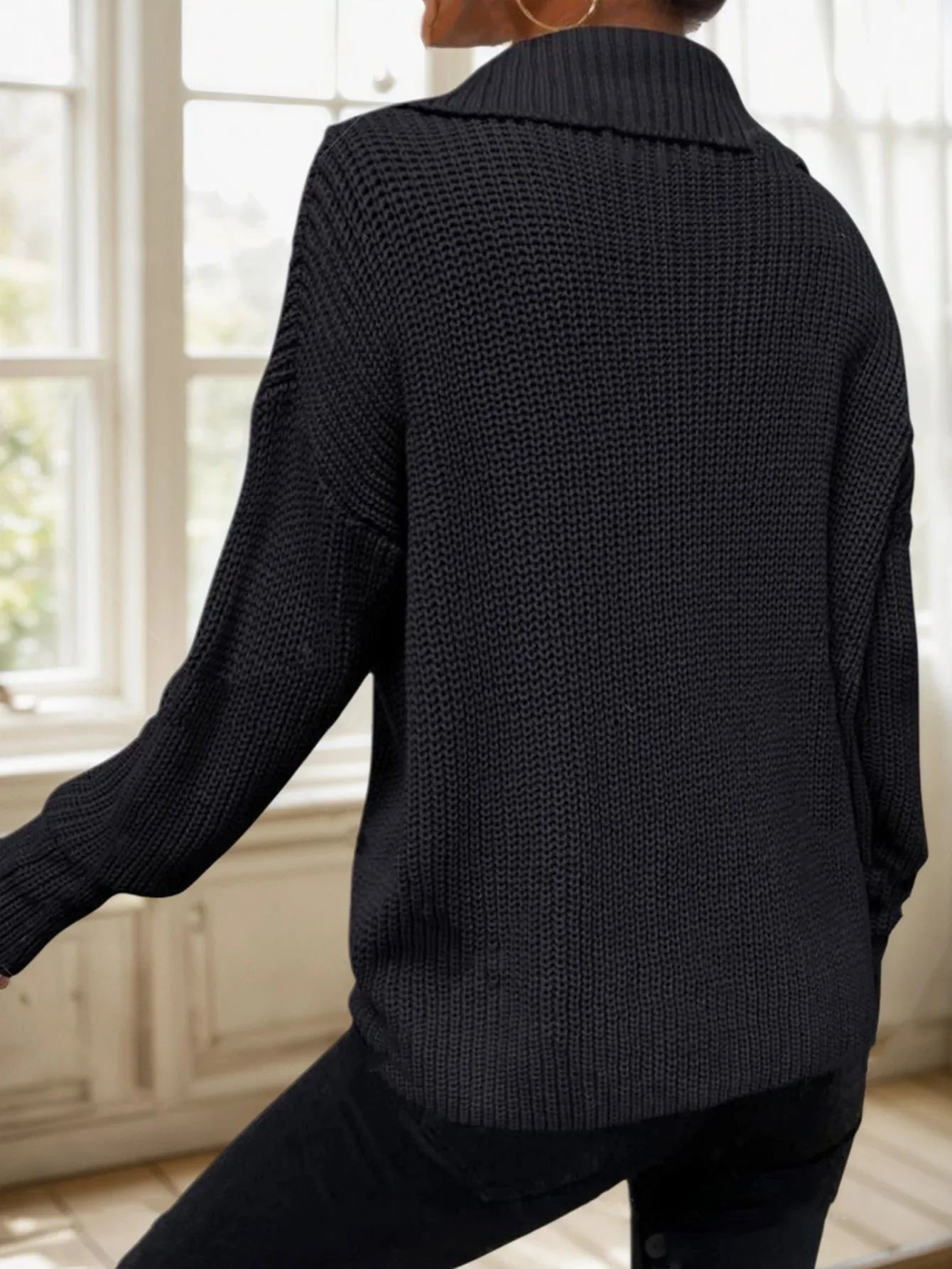 Back view of a woman wearing a black ribbed knit sweater.