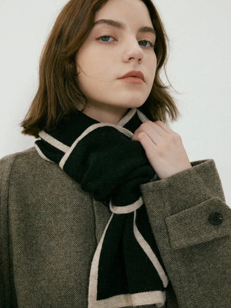 Close-up of a woman wearing a dark brown coat and a black and cream striped scarf