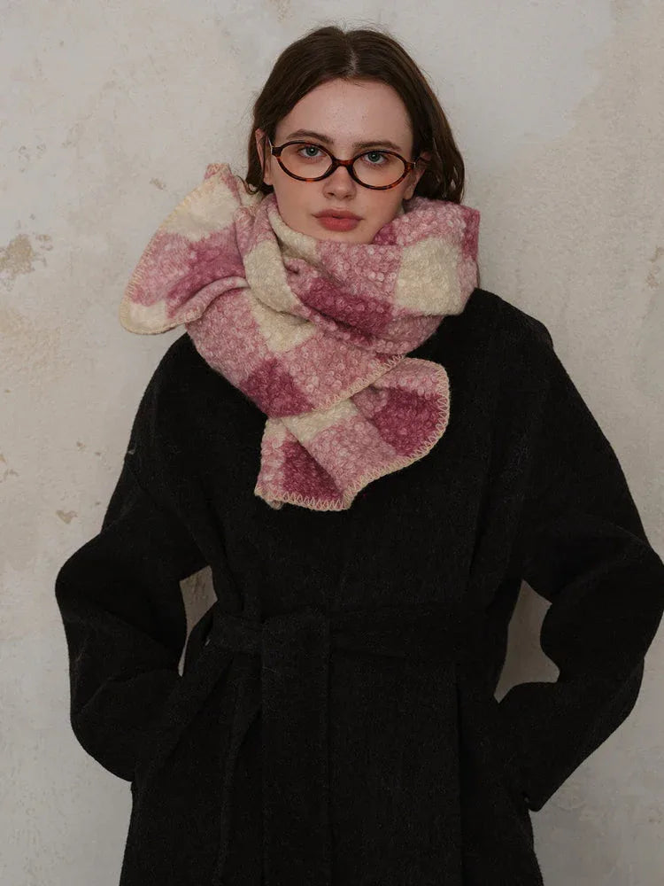 Close-up of a woman wearing a pink and cream plaid scarf wrapped around her neck.