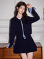 Woman wearing a navy blue knit cardigan and pleated skirt set with gingham details.