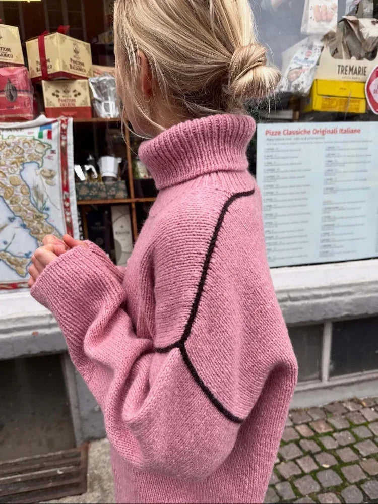 Close-up of the back of a pink oversized turtleneck sweater with contrasting black seam details. Secondary image