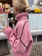 Close-up of the back of a pink oversized turtleneck sweater with contrasting black seam details.