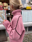 Close-up of the back of a pink oversized turtleneck sweater with contrasting black seam details.