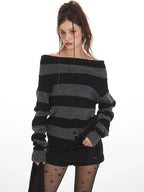 Model wearing a grey and black striped sweater styled off-the-shoulder, black shorts, black tights with stars, and black boots.