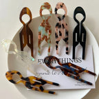 Collection of resin tweezers displayed on a white plate, showcasing different colors and patterns with a paper note.