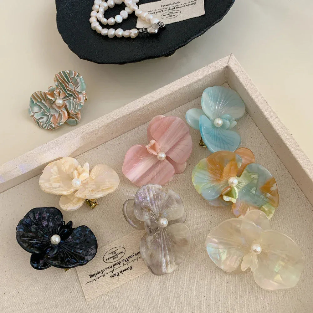 A collection of colorful floral hair clips arranged in a tray.