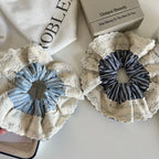 Two scrunchies side-by-side on a white surface, showcasing their ruffled lace edges and striped fabric.