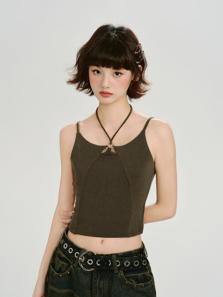 Woman wearing a dark olive green halter crop top with a ring detail at the neckline and a dark wash wide-leg jean with a grommet belt.