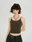 Woman wearing a dark olive green halter crop top with a ring detail at the neckline and a dark wash wide-leg jean with a grommet belt.