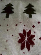 Close-up of the white knitted fabric with Christmas tree and snowflake print.