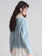 Rear view of a woman wearing a light blue knit cardigan with a white lace collar and cuffs.