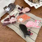 A group of cat-shaped hair clips are arranged on a textured fabric.