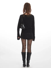 Back view of a woman wearing a black long-sleeve mini dress, star-patterned tights, and black boots.