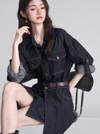 Woman wearing a dark wash denim shirt dress with a brown belt, sitting on a chair.