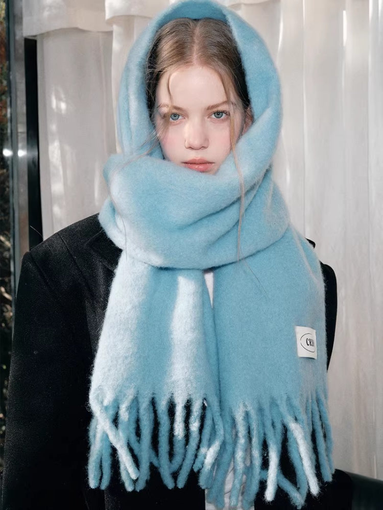 Close-up of a woman wearing a light blue fluffy knit scarf around her head and neck.