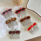 Several hair combs with bow and pearl details arranged on a white surface.