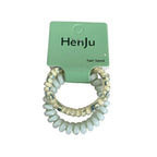 A pair of light blue spiral hair ties with beaded accents, packaged on a green card.