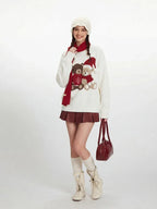 Model wearing a white fuzzy knit sweater with a graphic of two teddy bears, a red scarf, white beanie, red pleated skirt, white socks, and cream boots.