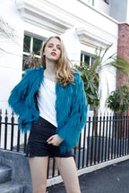 Full body shot of a woman in a teal faux fur jacket outdoors