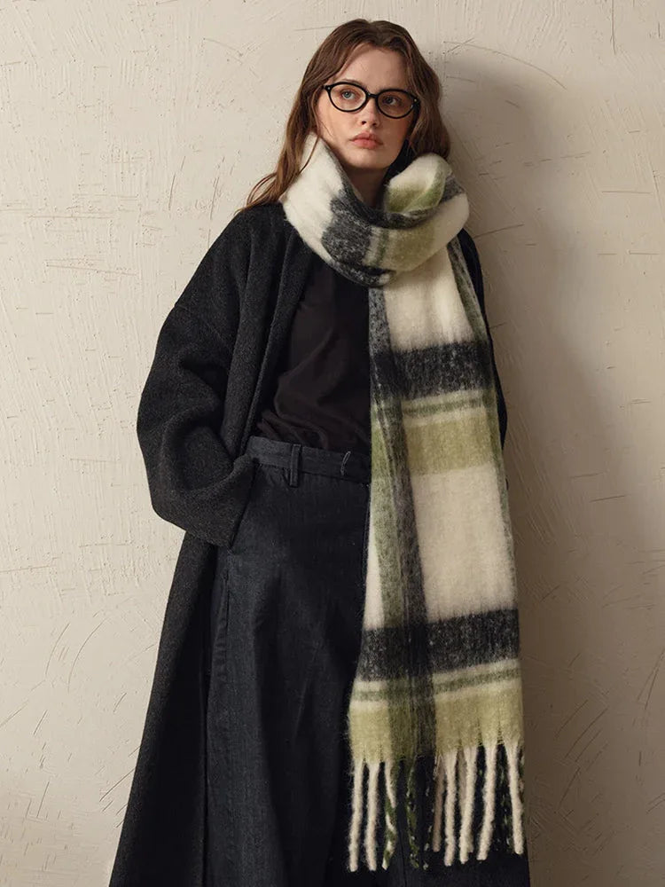 woman wearing a long dark coat and a green and white plaid scarf draped around her neck