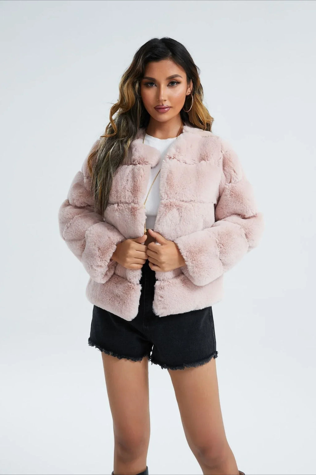 Woman wearing a taupe faux fur cropped jacket with a black dress.