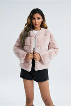 Woman wearing a taupe faux fur cropped jacket with a black dress.