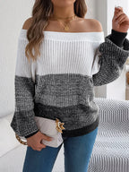 Woman holding a white handbag and wearing a color block off-the-shoulder knit sweater.