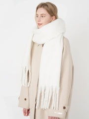 Woman wearing a white fluffy scarf draped over a beige coat, looking to the side