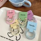 A grouping of colorful spiral hair ties with sparkly beads, presented on a white tray.