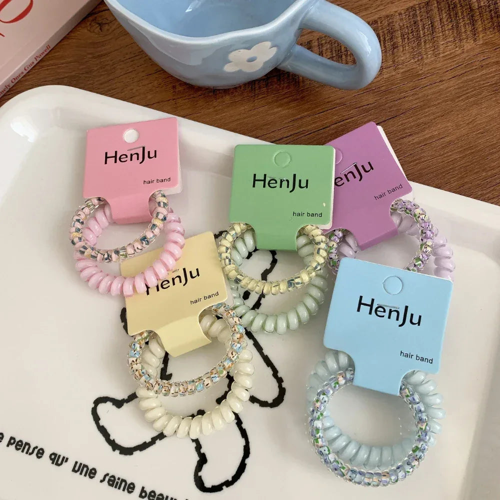 A grouping of colorful spiral hair ties with sparkly beads, presented on a white tray.