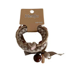 A close-up of a set of three braided hair ties with a heart charm and beads.