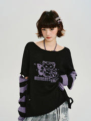 Model wearing a black knit sweater with purple graphic print and striped sleeves